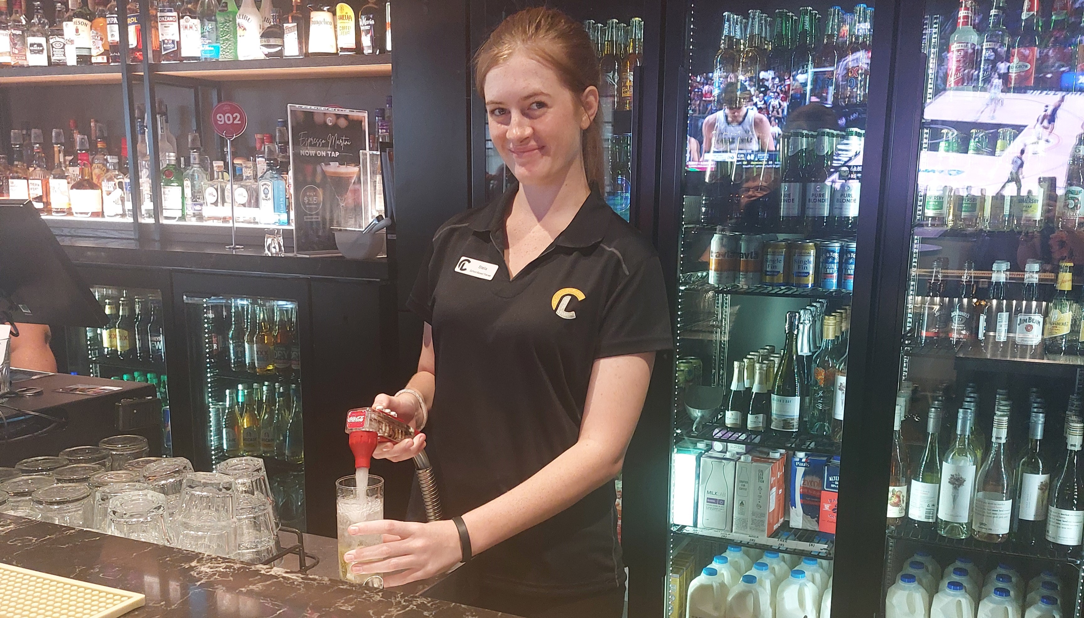 student working behind a bar preparing a beverage, reflecting industry-based training and workplace skills development